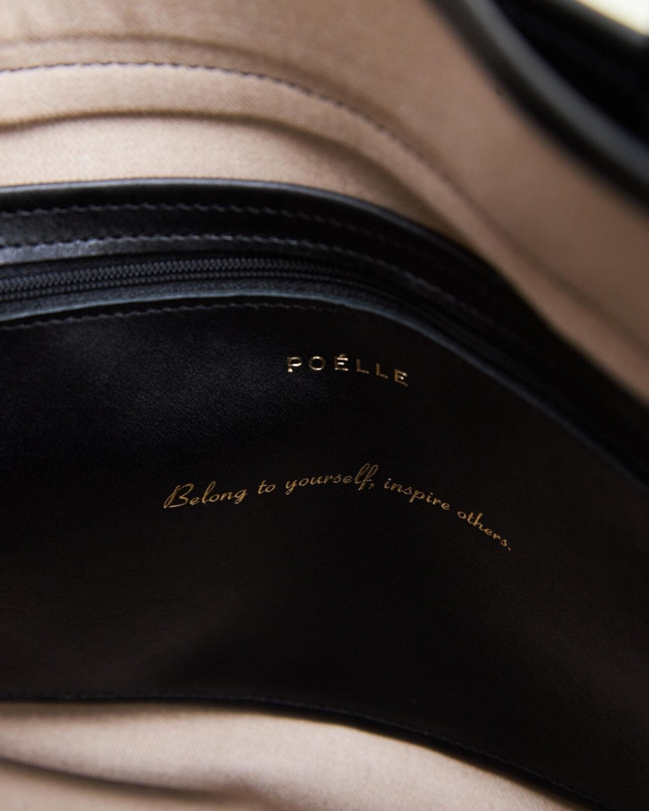 Interior close-up of Poelle Atelier luxury leather black bag with zipper and gold embossed logo