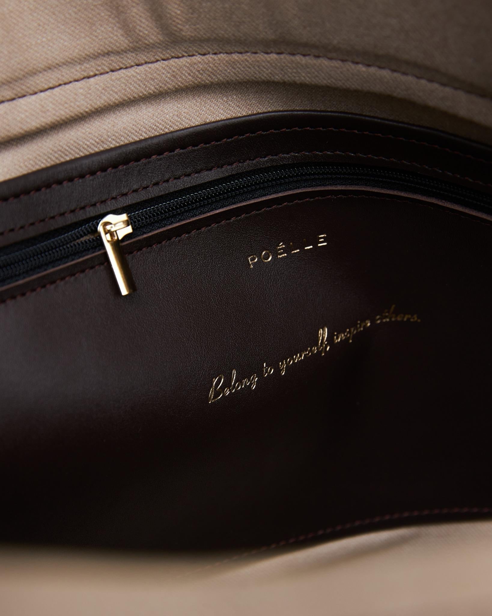 Close-up interior view of luxury leather brown bag with gold zipper and Poelle Atelier logo